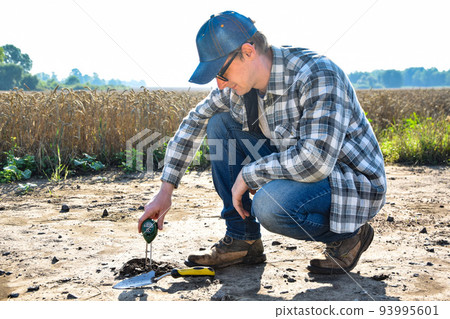 Agronomy specialist measuring soil pH value using soil tester outdoors 93995601