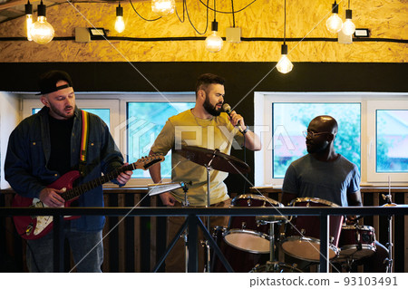 Portrait of three young intercultural men in casualwear having music repetition 93103491