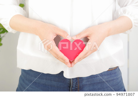 A woman with a heart mark in front of her stomach 94971807