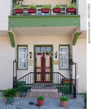 Old colorful wooden residential building with door, wrought iron windows and green climber plants, Istanbul, Turkey 95513803