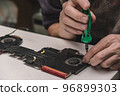 fixing fan in the laptop cooling system with screws and screwdriver. laptop maintenance. closeup. 96899303