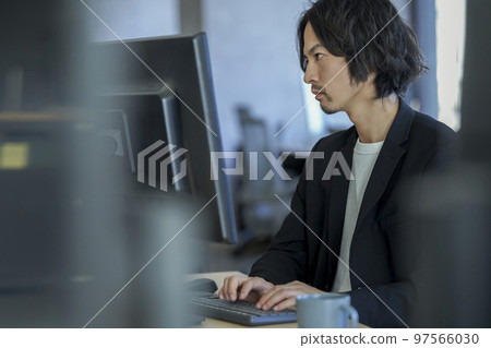 Profile of a man working on a desktop computer 97566030