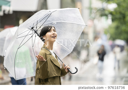 一個年輕女子拿著乙烯基雨傘仰望天空 97618736