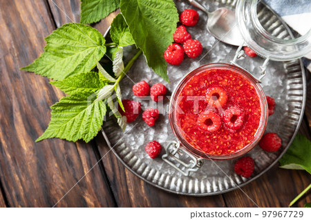 Homemade preservation. Delicious raspberries jam or jelly on a rustic wooden table. View from above. 97967729