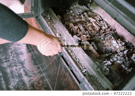 Fireplace cleaning. Woman hand holds a shovel with ash.A hand collects ash from the fireplace on an old steel blade. Daily winter routine 97222222