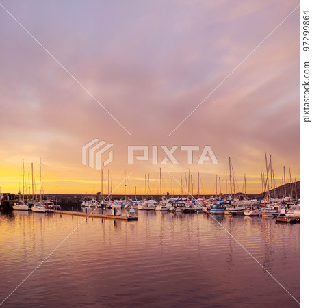 Scenic view of private yachts docked in water harbor at sunset in Bodo, Norway. Nautical transport vessels and boats in a dockyard in the morning at dawn before sailing on the ocean, sea or lake 97299864