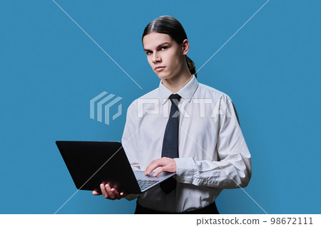 Handsome young male using laptop on blue studio background 98672111