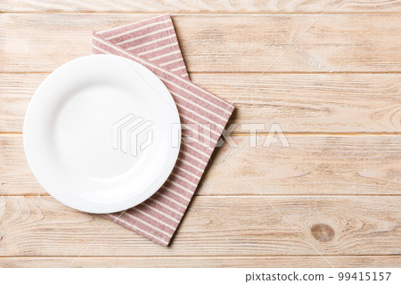 Top view on colored background empty round white plate on tablecloth for food. Empty dish on napkin with space for your design 99415157