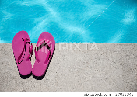 Pink slippers near swimming pool 27035343