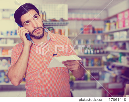 Portrait of adult male with note and smartphone in market. 37061448