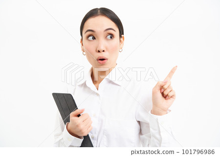 Image of young professional woman, pointing finger right, holding digital tablet, showing advertisement campaign, isolated on white background 101796986