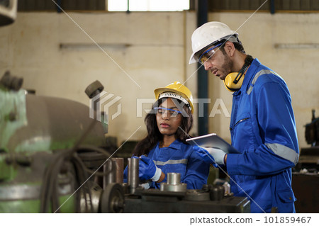 Team of mechanical engineer working together in the factory, engineers inspecting a metal machine system the factory. Female and male mechanical technician fixing a machines. 101859467