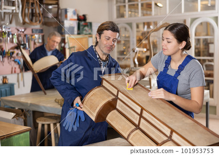 Man and woman are working on restoration of vintage chest of drawers together in restoration workshop 101953753