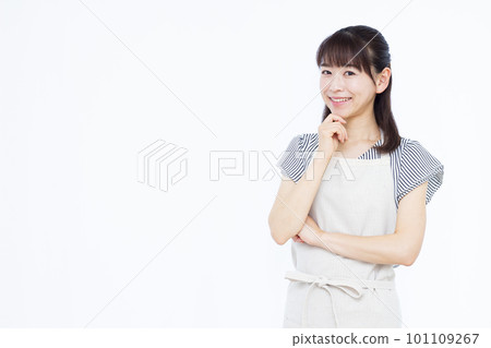 A housewife in her thirties wearing an apron thinking with her arms folded and smiling 101109267