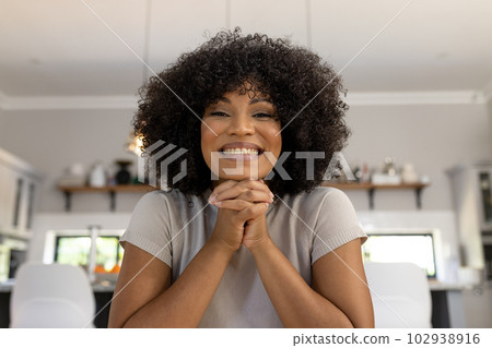 Portrait of excited, happy biracial woman with afro sitting at home making video call, and smiling 102938916