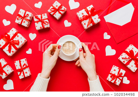 Flat lay of heart shaped cup of black coffee in the hands of women on colored background with copy space top view. Valentine day and holiday concept 102034498