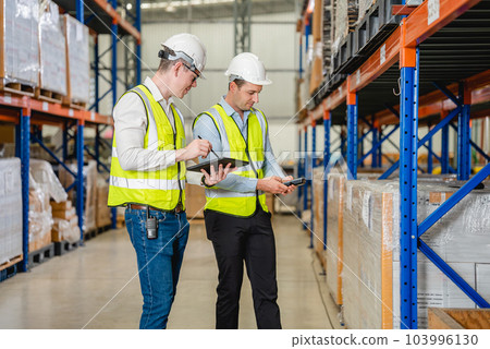 Warehouse workers talking together checking goods in storage 103996130