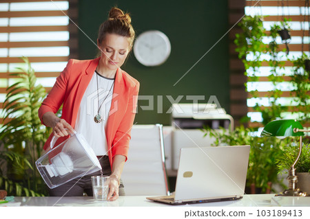 modern business woman at work in red jacket with cup of water 103189413