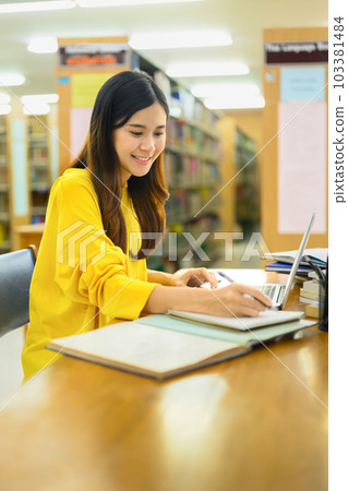 Portrait of asian female student doing class assignment and searching information on laptop in library. Education concept 103381484