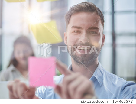 businessman is working on a project. Business man pointing at a note on the glass wall in the office. 104463578