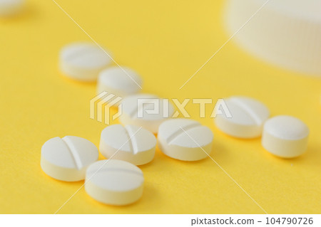 white pills on yellow background 104790726