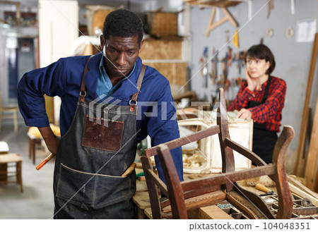 Craftsman restoring old chair in studio 104048351