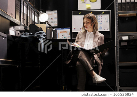 Corporate manager checking administrative record, analyzing accountancy report working overtime in arhive room. Businesswoman reading bureaucracy files, planning strategy to catch mysterious suspect 105526924