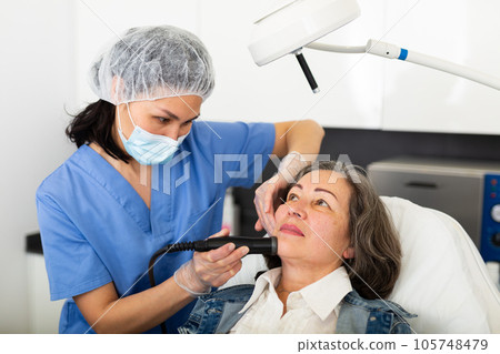 Elderly woman getting facial procedure in aesthetic medicine office 105748479