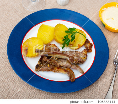 Grilled lamb spare ribs with baked potatoes garnished with greens 106222343