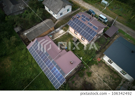 Man technician mounting photovoltaic solar moduls on roof of house. Mounter in helmet installing solar panel system outdoors. Concept of alternative and renewable energy. Aerial view. 106342492