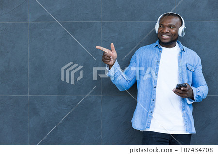 A stylish, young African-American man listens to music in headphones 107434708