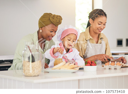 Gay family, child and cooking in home kitchen for learning, development and love. Adoption, lesbian or lgbtq women or parents and a happy young kid together to cook breakfast food with care and help 107573410