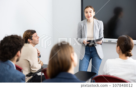 Young female teacher giving lecture to group of student 107848012