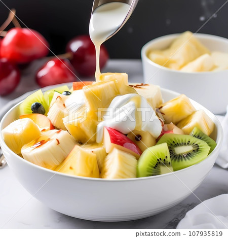 Healthy breakfast fruit salad kiwi bananas pineapple in white bowl on table 107935819