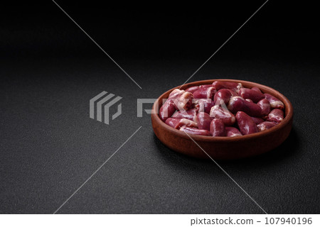 Fresh raw chicken, turkey or duck hearts on a ceramic plate with salt and spices 107940196