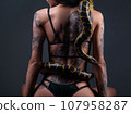 Photo of the sitting woman with crawling yellow anaconda on back 107958287