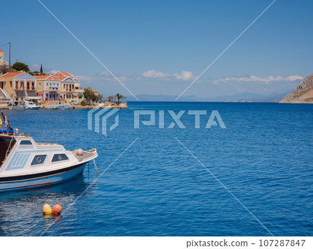 View on Symi or Simi island harbor port, classical ship yachts, houses on island hills, Aegean Sea bay. Greece islands holidays vacation travel tours from Rhodos island. Symi, Greece, Dodecanese. 107287847