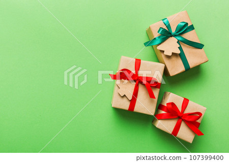 wrapped christmas or other holiday handmade present in paper with colored ribbon. Present box, decoration of gift on colourfull table, top view with copy space 107399400