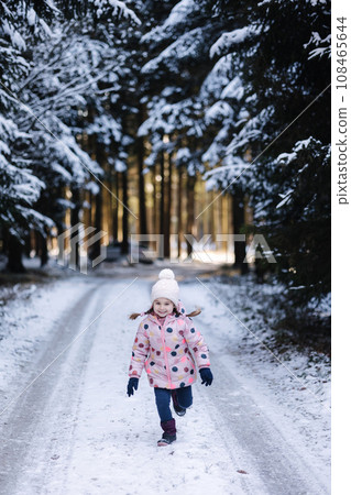 Adorable little girl run in snowy forest. Holiday mood 108465644