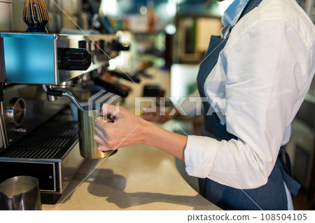 Coffee shop assistant preparing coffee in a coffee store 108504105