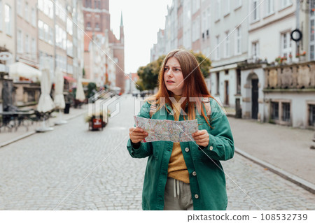 Portrait beautiful woman with paper map on urban street. Young worried female traveler lost in the city using map. Vacation concept by exploring interesting places to travel. 108532739