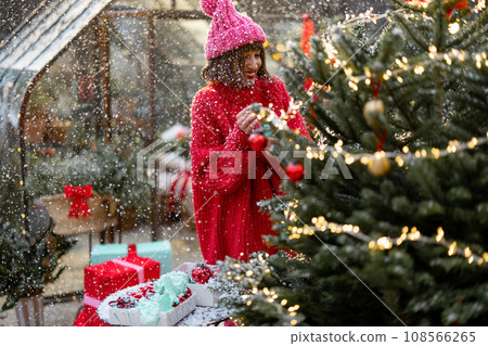 Woman decorates Christmas tree at bacyard 108566265