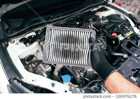 Car air filter is clogged and there are stains on the air filter in the hands of the car mechanic 108976276