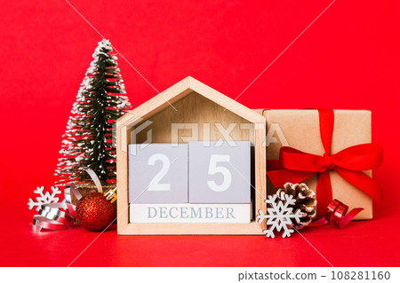 25 december. Christmas composition on colored background with a wooden calendar, with a gift box, toys, bauble copy space 108281160