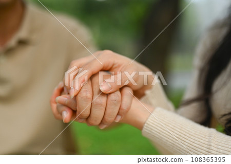 Close up affectionate adult daughter covering wrinkled hands of mature father showing love and support 108365395