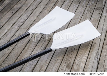 blades of hatchet sculling oars against grunge, rustic wooden deck 109465204