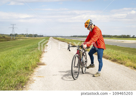 athletic senior cyclist with a gravel touring bike on a levee trail along Chain of Rocks Canal near Granite City in Illinois 109465203