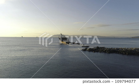 View of a old sunken ship on a shoal in sea against the sunset sky and mountains. Shot. Old seagoing vessel 109794077