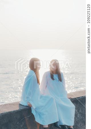 Two young women having a conversation on the beach 109225120