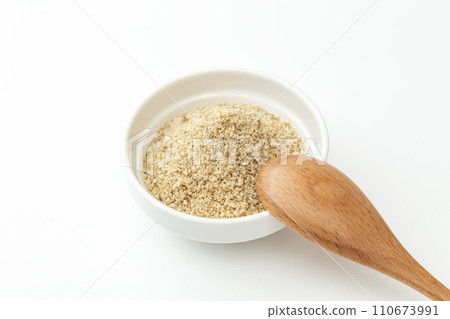 Ground sesame seeds and wooden spoon in a bowl, white background 110673991